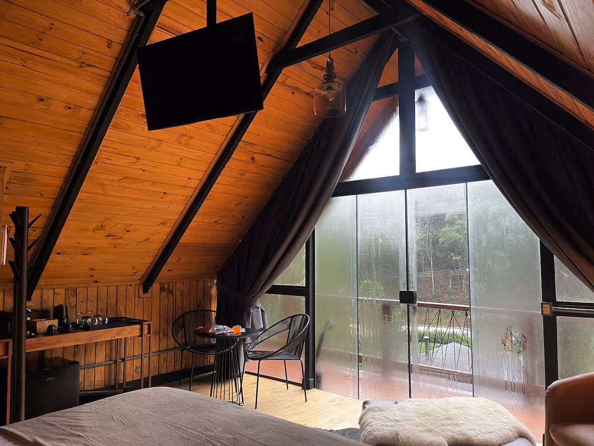 Janela triangular A-frame emoldurando as araucárias